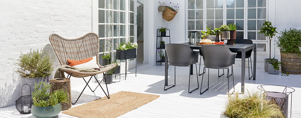 Patio with a garden set, lounge chair and a lot of planter boxes, flower pots and tall planters  