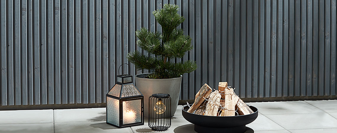 A lantern, a solar lamp, a fire pit and a garden planter on a patio