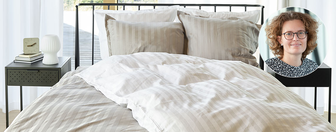 Bedroom with bed, duvets and pillows, covered in striped bedding and insert of Berit Christiansen