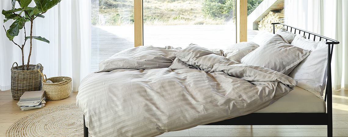 ABILDRO bed frame with duvets and pillows, covered in NELL duvet cover set in light grey and white Bedroom with black metal bed, duvets and pillows, covered in striped bedding in light grey and white