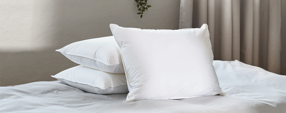 Stack of three pillows without covers on a bed