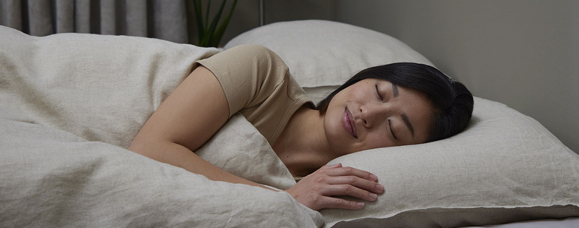 Soft, medium firm, firm or very firm mattress? Woman sleeping in bed with white pillow and duvet
