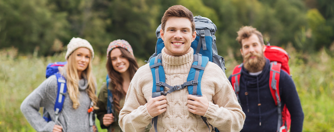 Smiling group of backpackers hiking in forested area