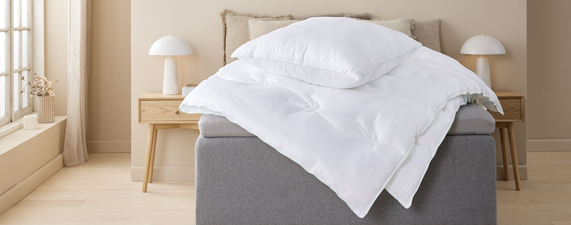 RINGSTIND duvet and pillow have cover in 100% viscose, made from bamboo, combined with aloe vera treatment Duvet and pillow with cover in bamboo viscose fabric on top of bed in light bedroom