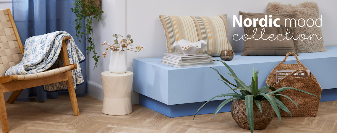 VADEHAVET armchair, SOMMEREIK quilted blanket, CARLO vase, SIGMUND pedestal, BELLIS, NATTLILJA and MYRFIOL cushions, SIVERT plant pot with CELIUS artificial plant and MICHAEL basket Stoneware vase on pedestal, white bowl, artificial plant in wicker plant pot, and cushions on bench