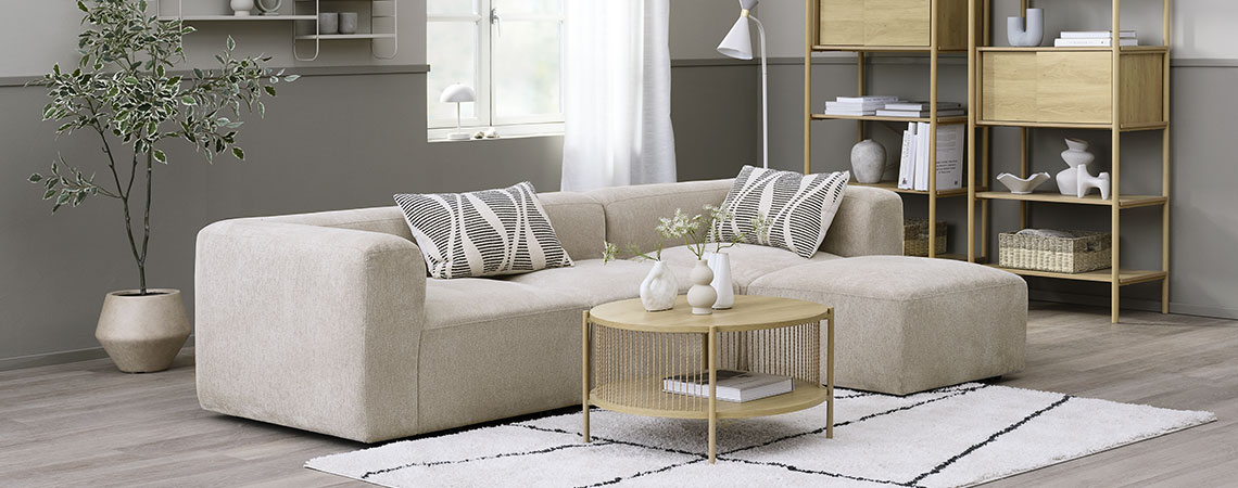 SKEJBY modular sofa Beige modular sofa in a living room area together with a coffee table, bookcases, and a plant