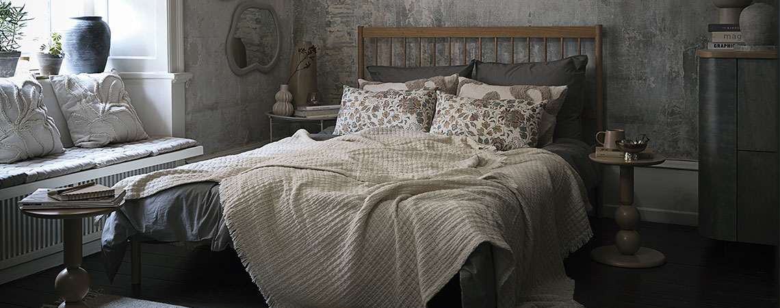 Rugs, throws, and cushions add hygge to your room styling Bed with cushions and throws in beige and green tones