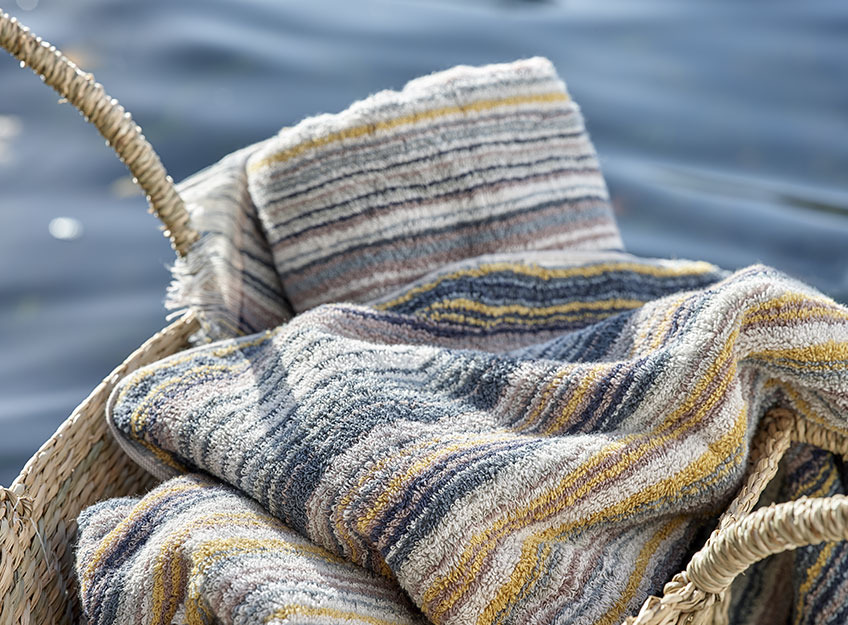 SEGERSTA towels are available in two different colour combinations Striped towels in a basket by a lake