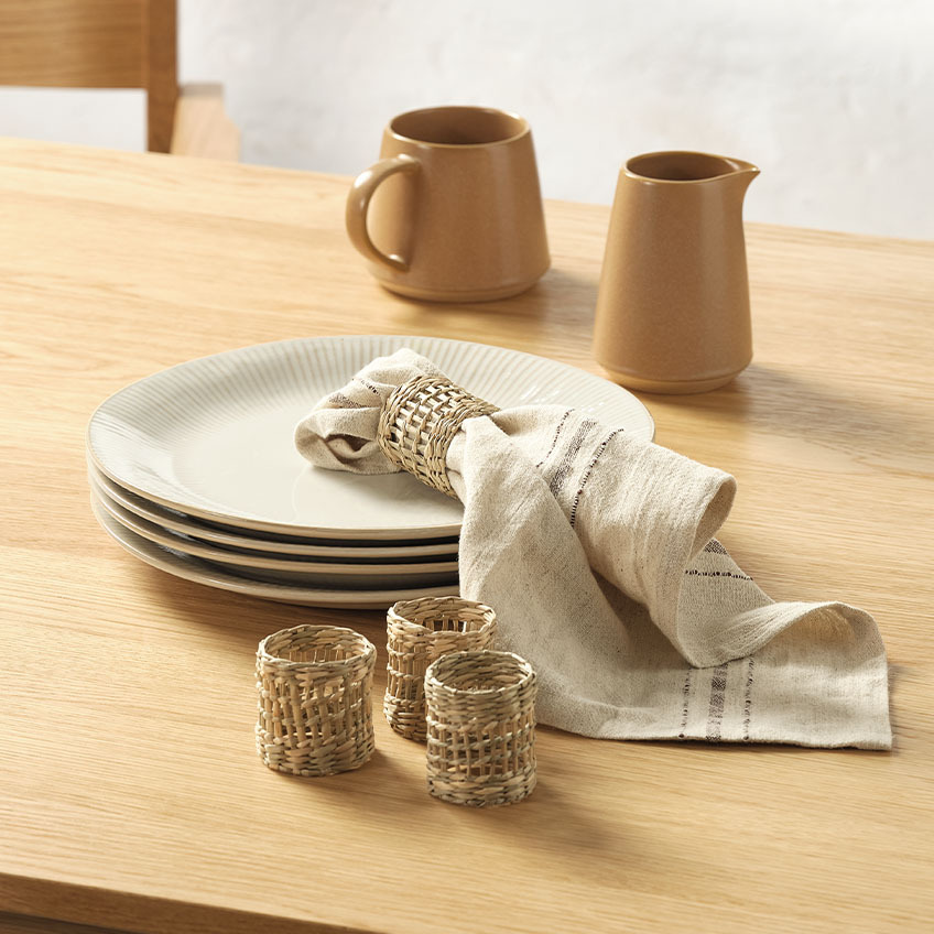 STEFFEN fluted plate, KASTANIE cloth napkin, PATRICK napkin rings, and OLLE milk jug White fluted dinner plates, milk jugs, cloth napkin, and napkin rings on dining table