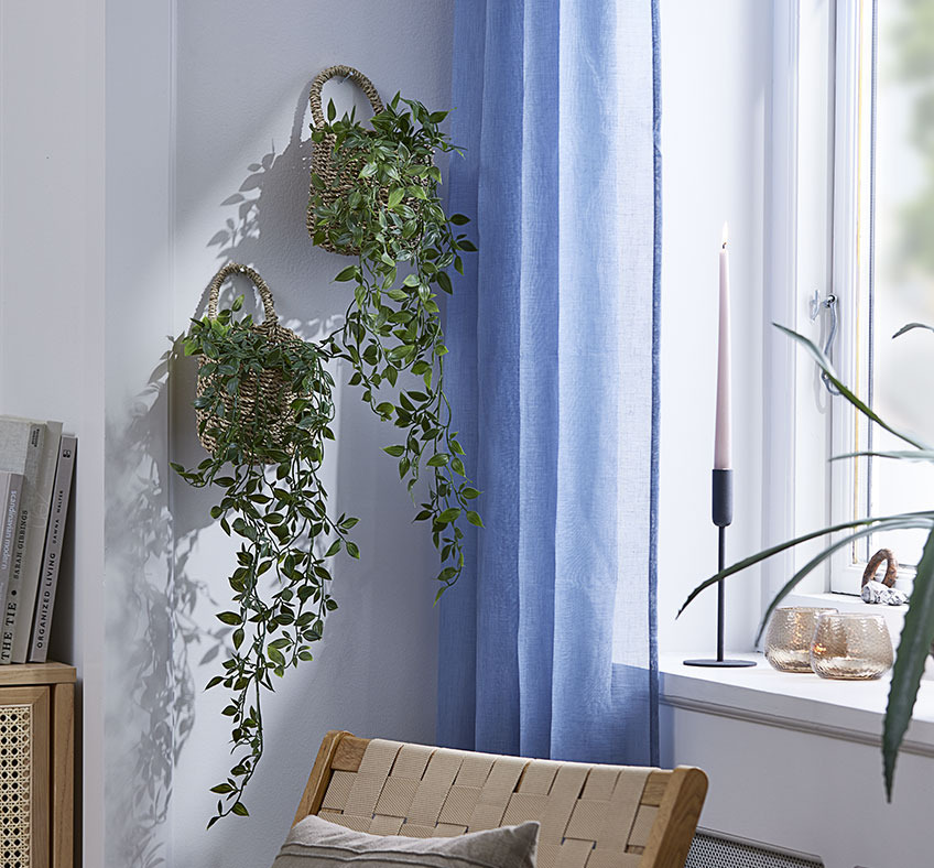 INGVER basket with OLIVER artificial plant Two baskets with artificial plants hanging on a living room wall