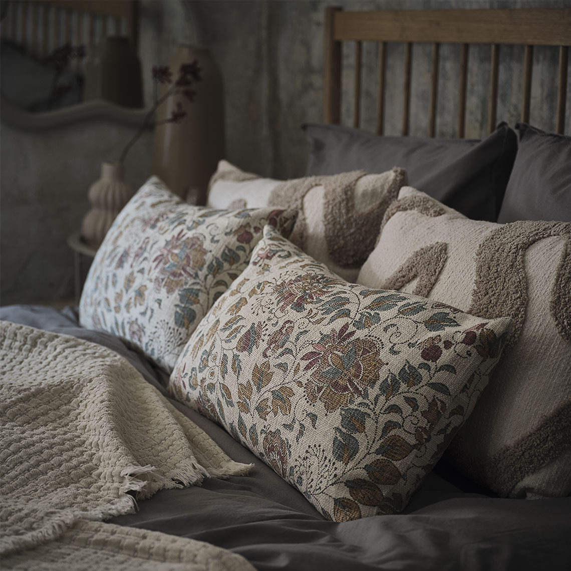 HYBENROSE cushion and LYNG cushion Floral printed and beige cushions in a bed with a beige throw