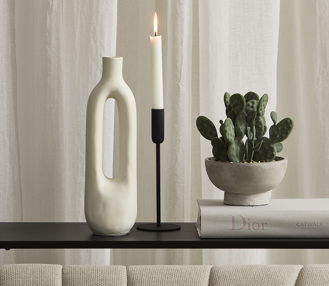 White vase, black candlestick and artificial plant in pot