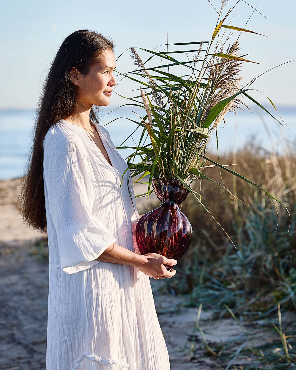 VILMER vase Woman holding glass vase with organic shape on beach