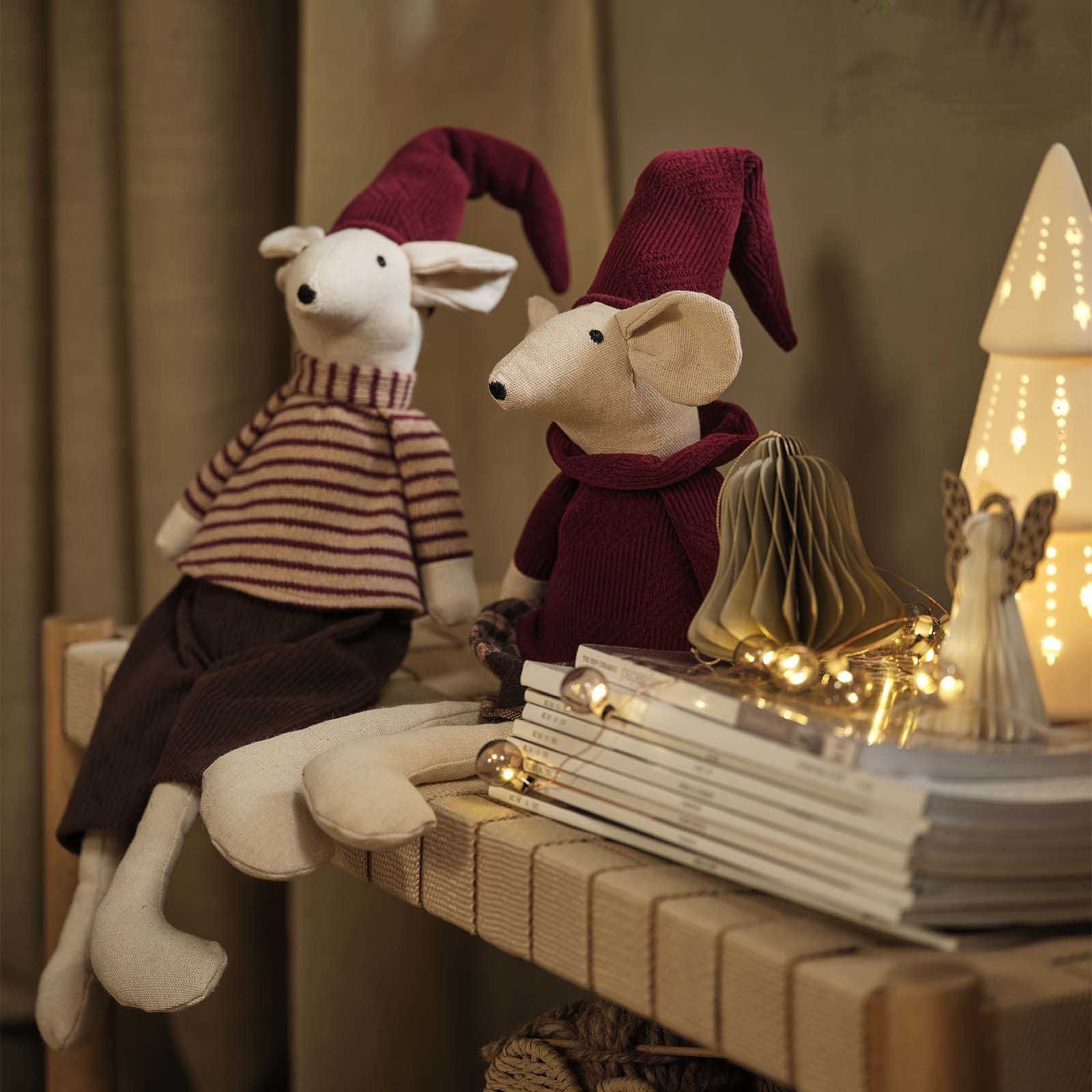 Decorative Christmas mice with pointy Christmas hats in burgundy on a daybed