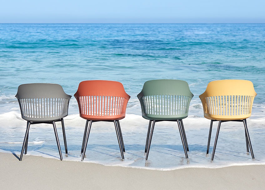 RAVNEBAKKE garden chairs available in grey, red, green and yellow Four garden chairs in different colours on a beach
