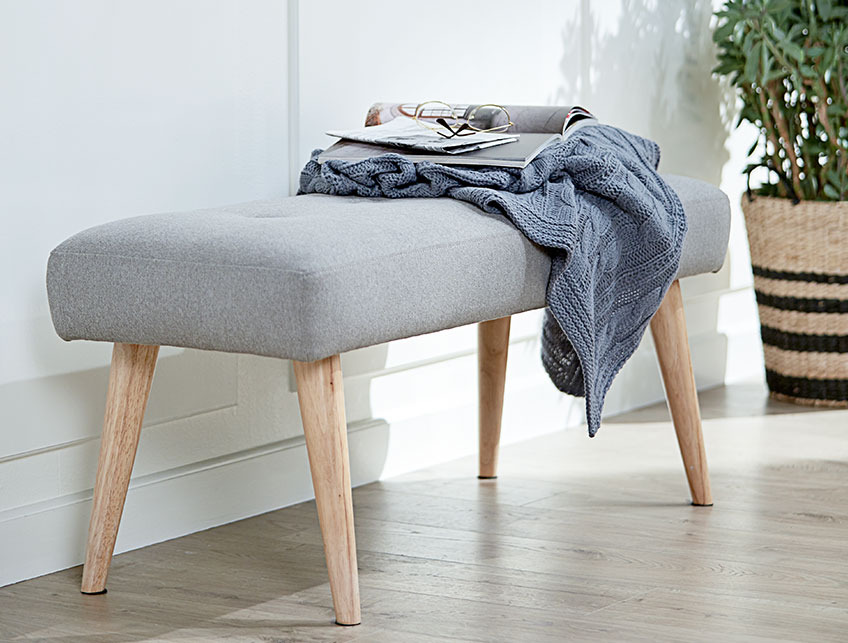 The EGEDAL bench with wooden legs A grey bench with wooden legs in a hall