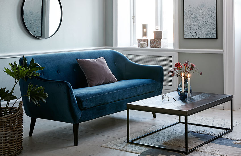The EGEDAL sofa in blue velvet and the HALSKOV coffee table A living room with a blue velvet sofa and a coffee table