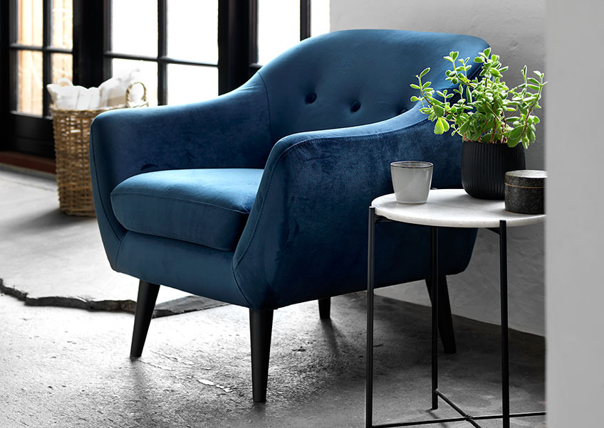 The EGEDAL sofa in blue velvet and the HAARBY coffee table A living room with a blue velvet armchair and a coffee table