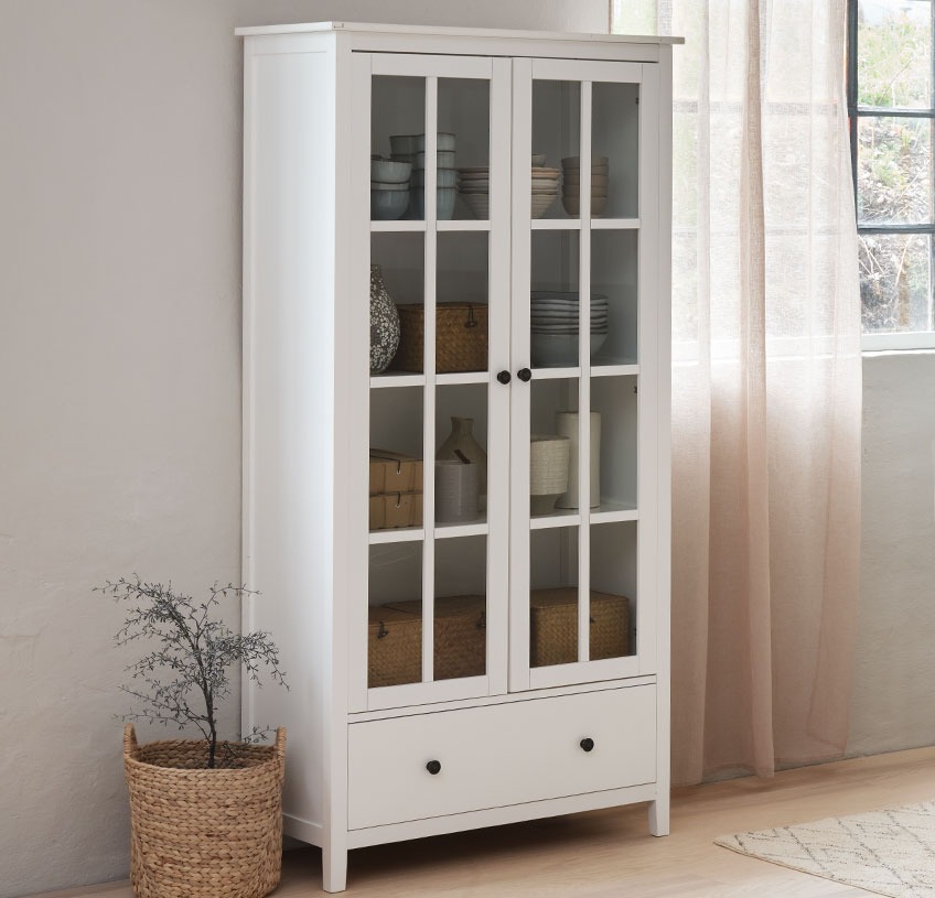 NORDBY cabinet with glass doors and one drawer White cabinet with glass doors by the window in a light room
