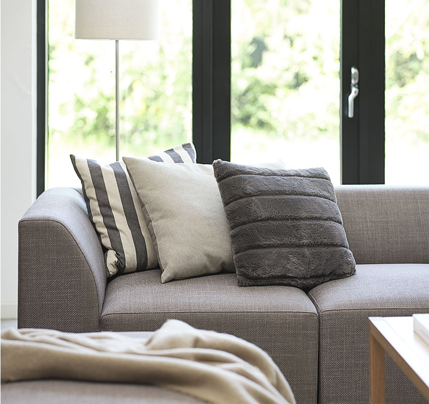TERNDRUP sofa built of modules and VALERIANA, LILJE and STAVKLOKKE coffee table Grey modular sofa with three decorative cushions in Scandinavian living room